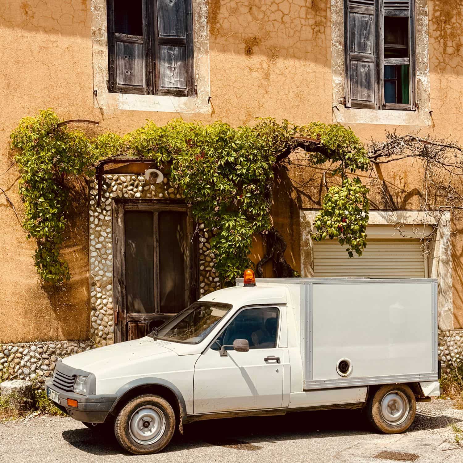 White Citroën C15 parked beneath plane trees in a sunny village in Provence