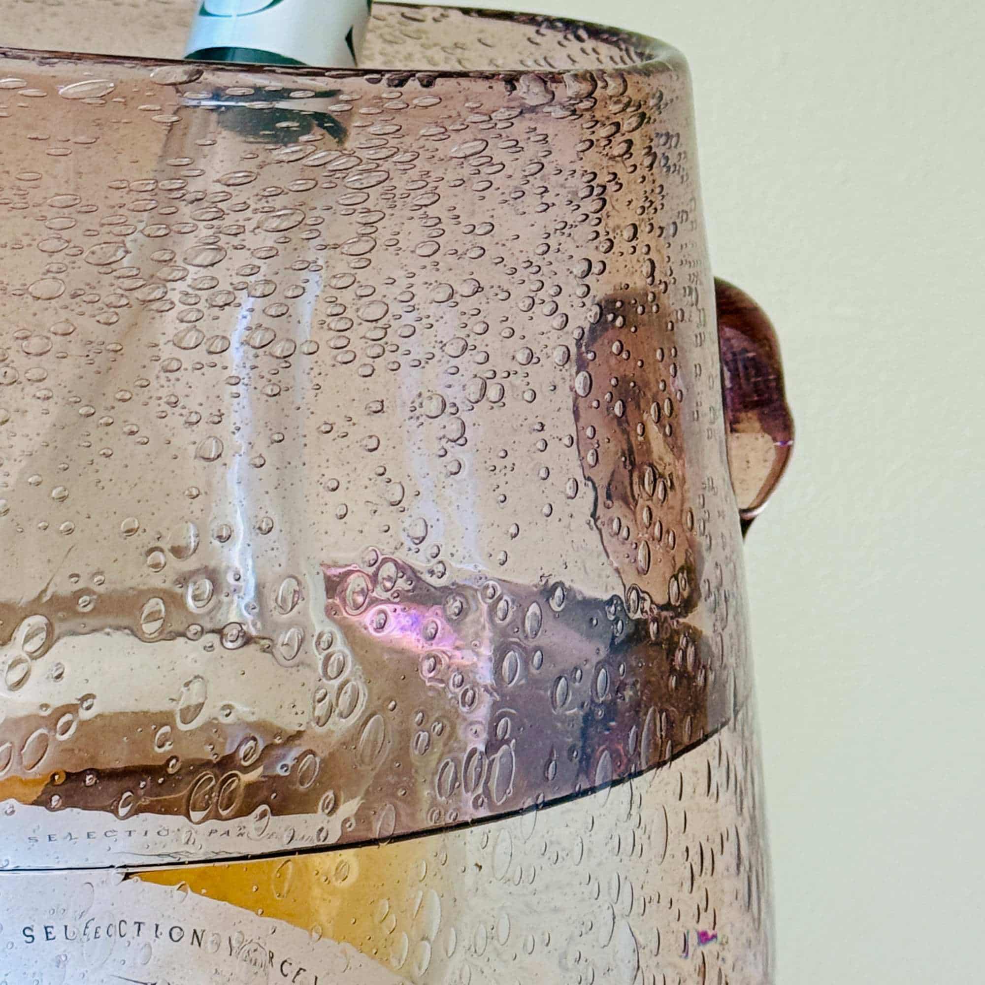 Rose coloured French glass wine bucket holding a bottle