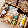 Gift basket with various items including a bottle of olive oil, a jar of spread, and a box of cookies.