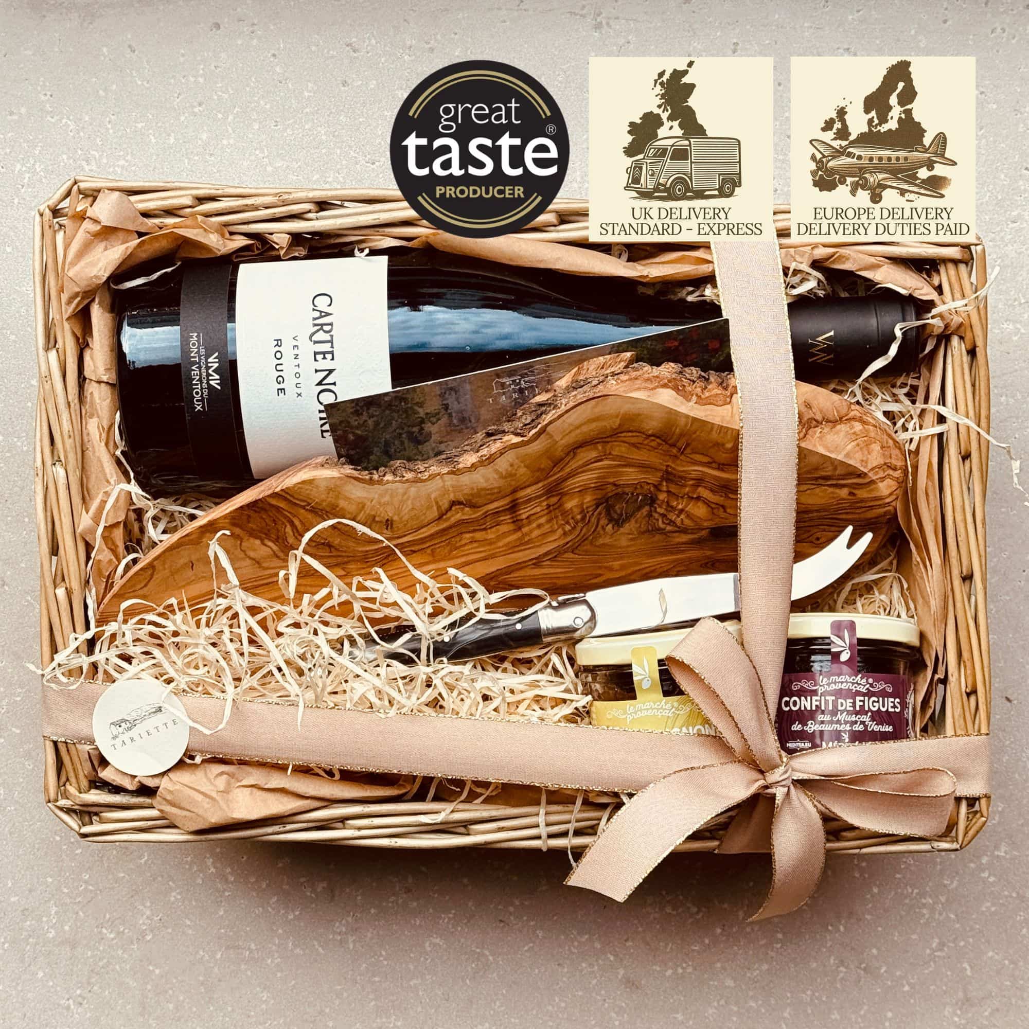 The Tariette Fromage Box is a delicious French gift for cheese lovers, featuring artisan chutneys, a Ventoux red wine, and a beautiful olive wood board with a Laguiole knife.