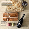 Fromage Box contents laid out: olive wood cheese board, Laguiole cheese knife, red wine, fig and onion chutneys.