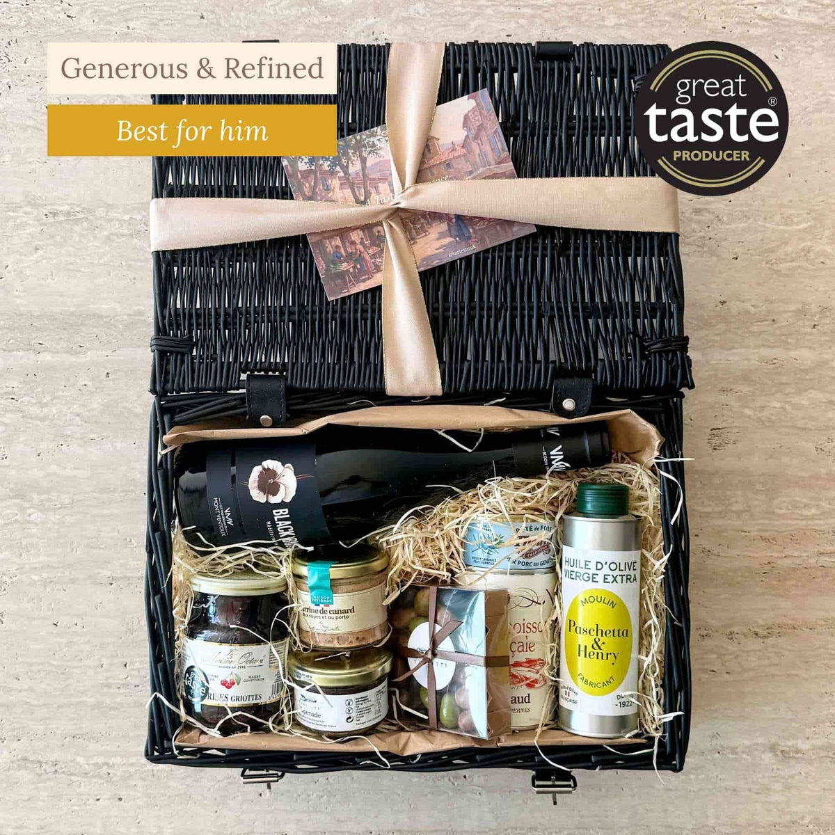 Tariette Gaspard French food hamper in a black wicker basket with red wine, olive oil, terrine, pâté, fish soup and chocolate almonds.