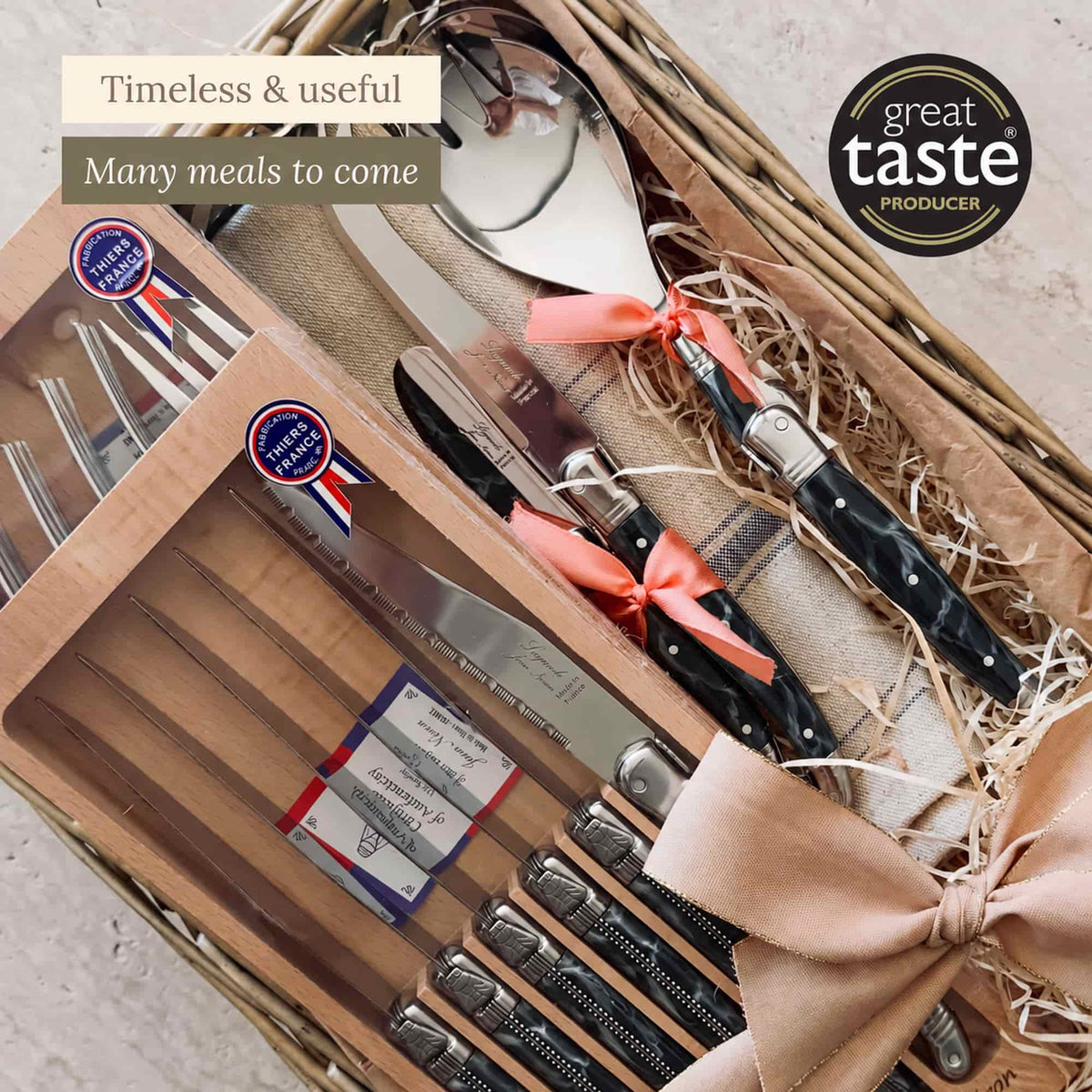 Close-up of the Laguiole cutlery gift basket showing boxed knives and forks, salad servers and a linen tea towel.