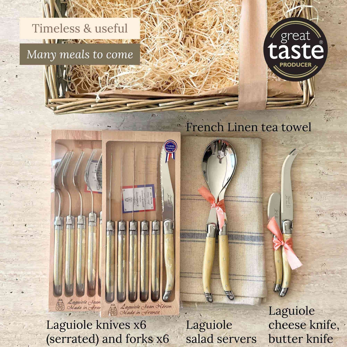 Laguiole gift box contents laid out: six knives, six forks, salad servers, cheese and butter knives and a French linen tea towel.