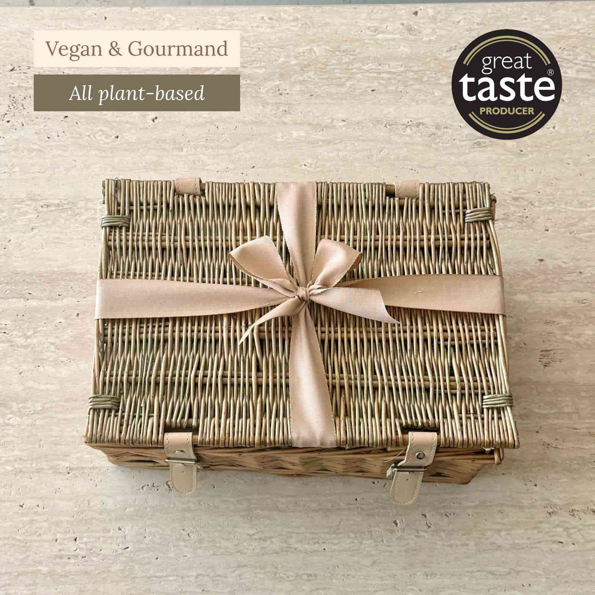Tariette Lio vegan gift hamper in a closed wicker basket tied with a pale pink ribbon.