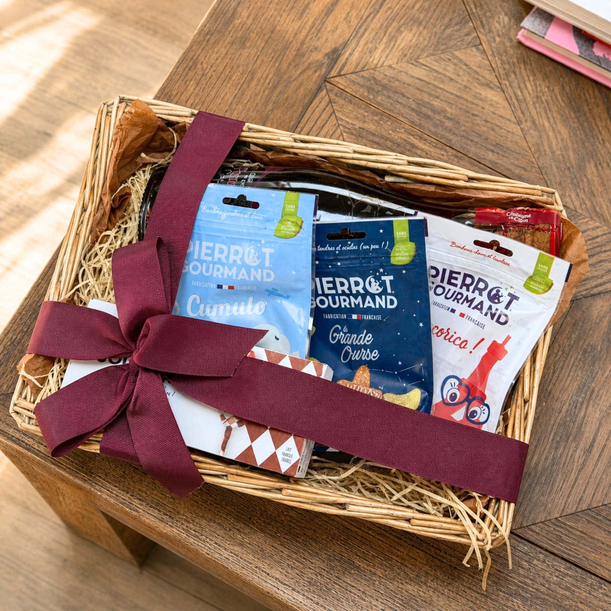 French sweet shop set in a wicker basket with Pierrot Gourmand sweets and caramel lollipops, tied with a burgundy ribbon