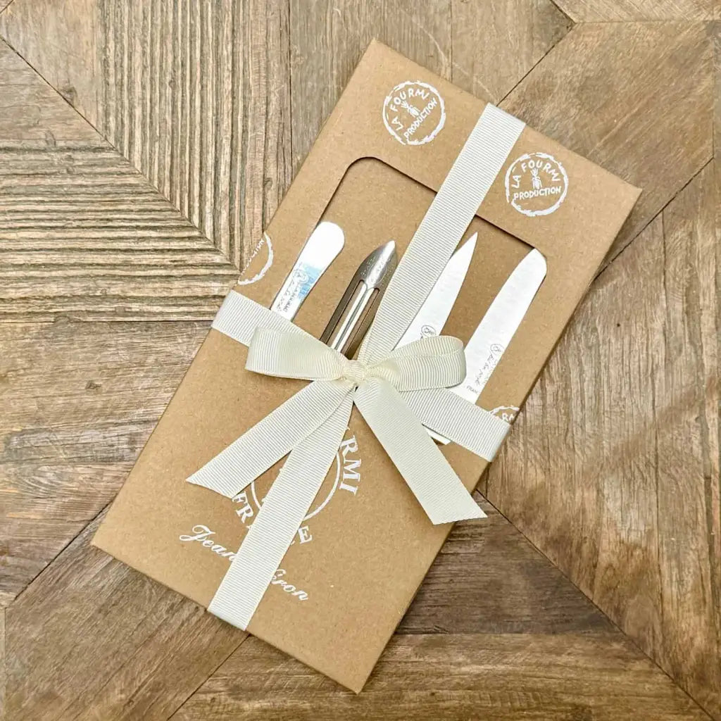 Set of cutlery in a brown box with a white ribbon on a wooden surface